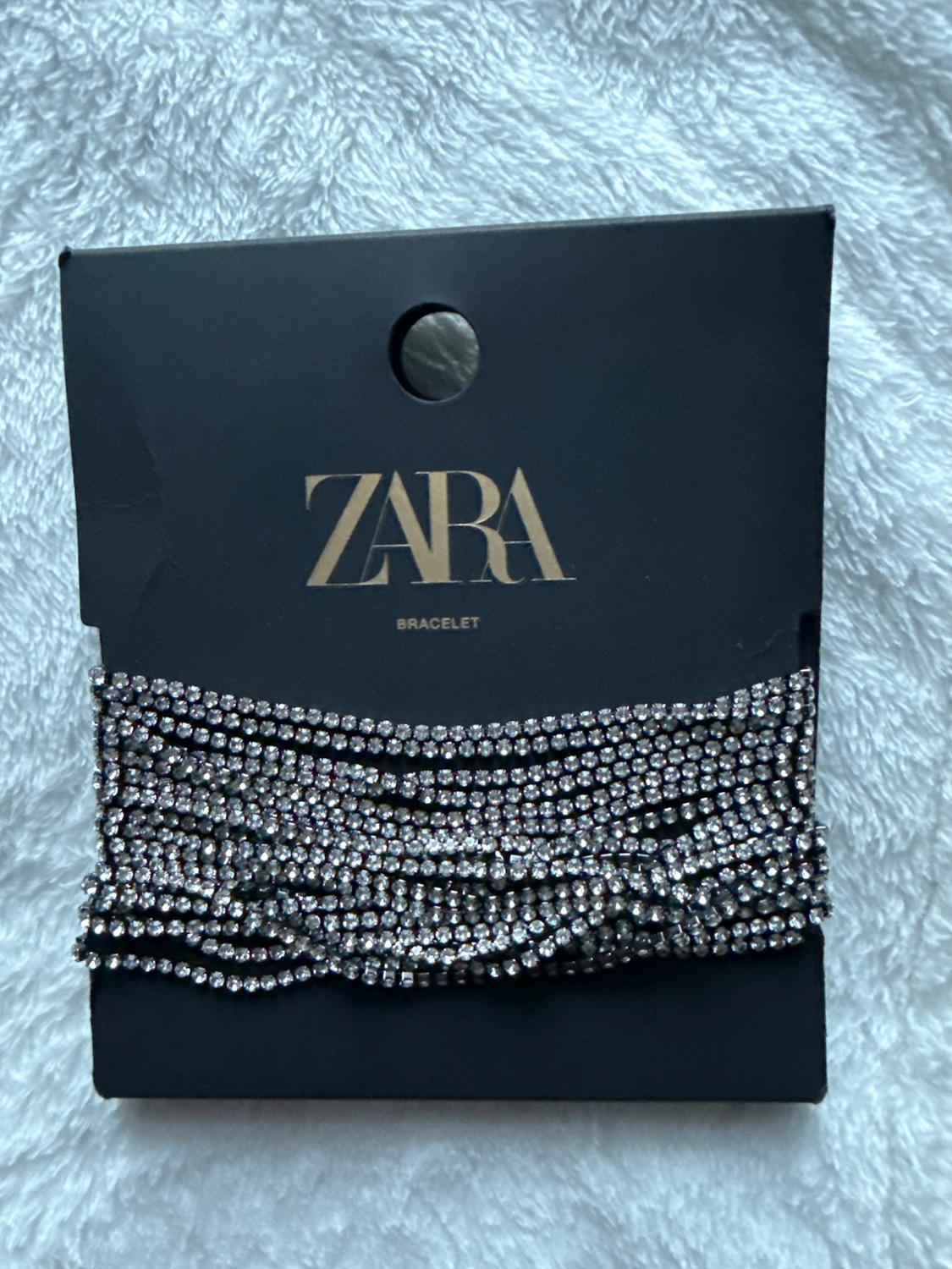 Multi-row rhinestone bracelet on a black background with the text "ZARA BRACELET" in gold letters.
