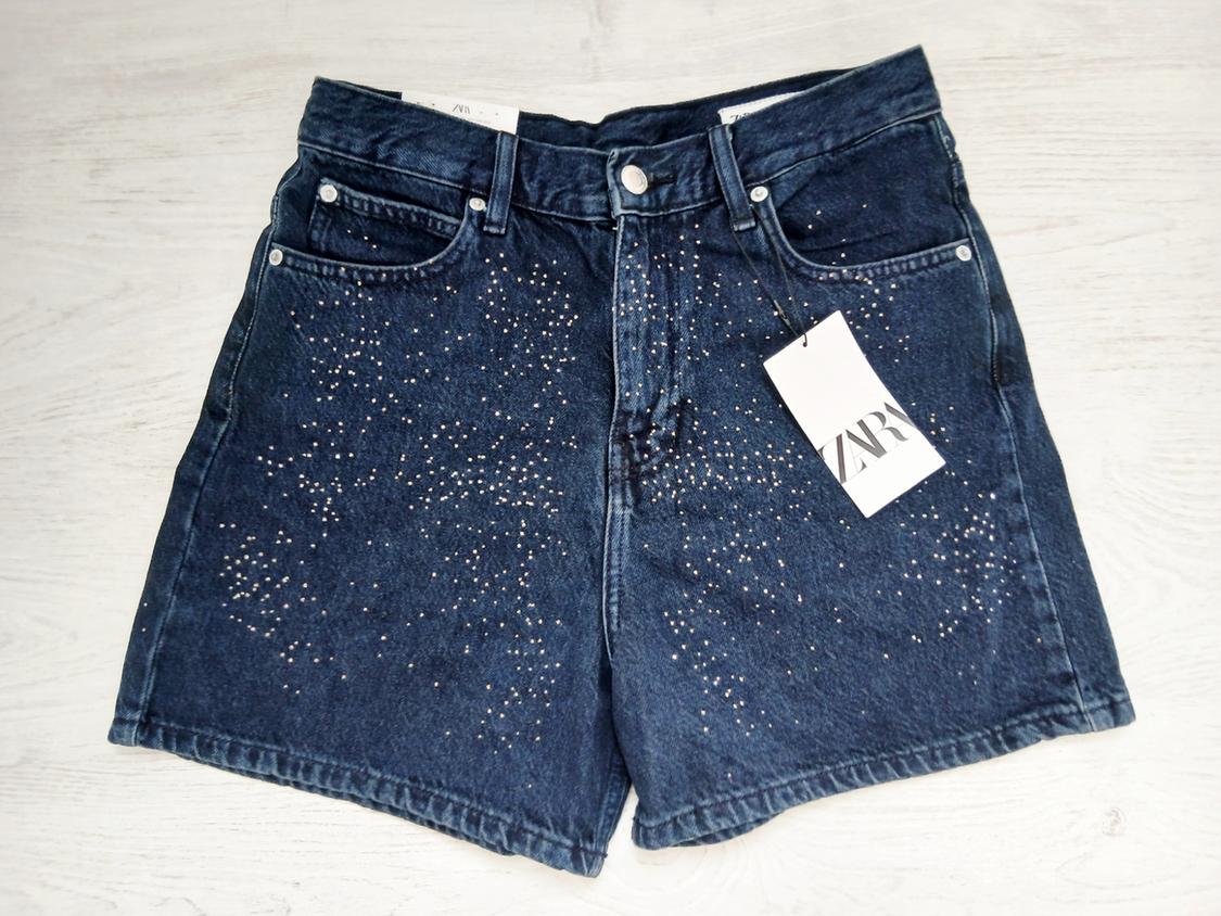 Dark blue denim shorts with sparkly details and a ZARA tag on a white background.