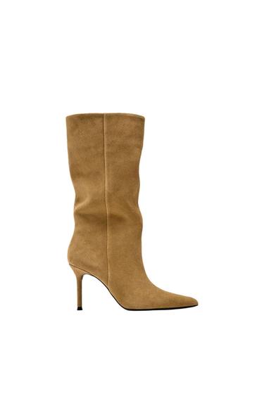 High-heeled camel boot, with a minimalist design and pointed toe, on a white background.