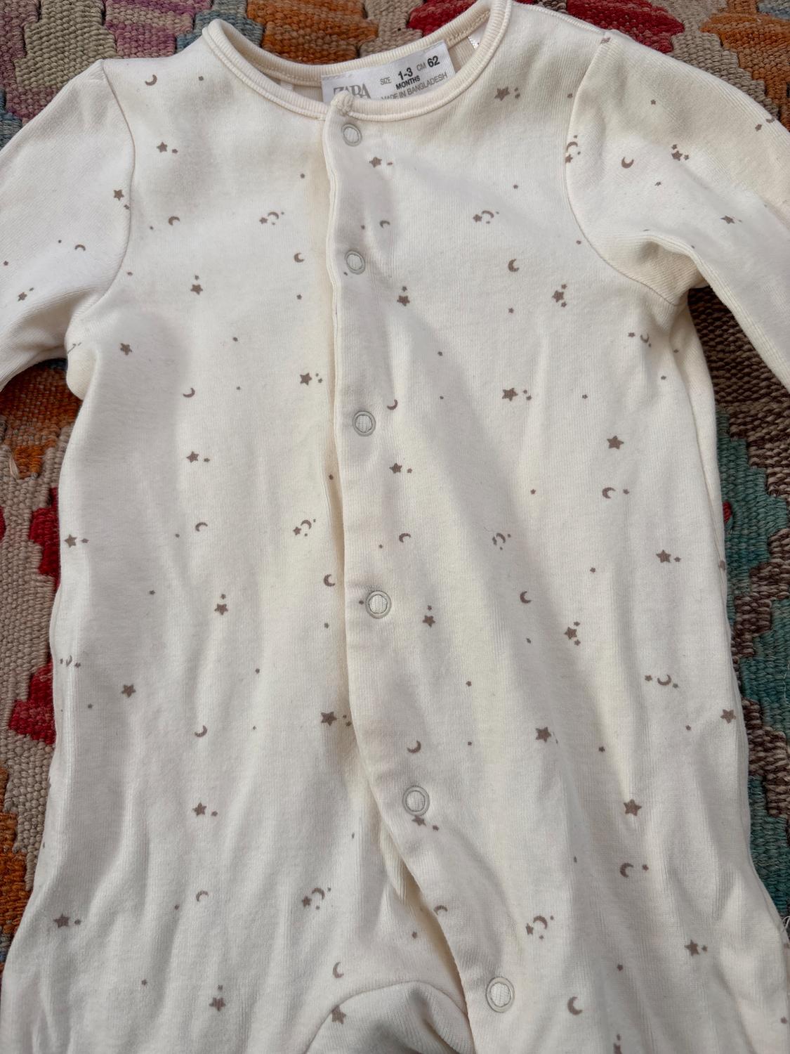 Front view of a white bodysuit with a star and moon print, front button fastening.
