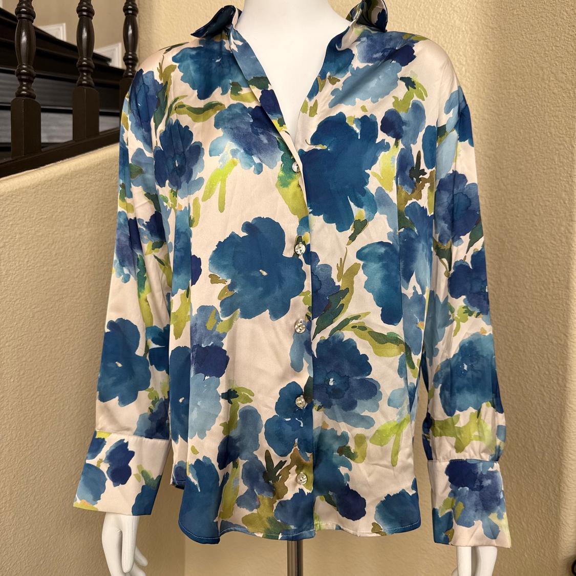 Mannequin wearing a long-sleeved, button-down shirt with a floral print in shades of blue and green, set in a relaxed indoor environment next to a staircase.