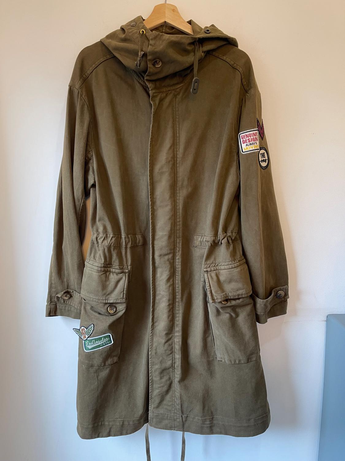 Olive green coat with a hood and patches on the sleeves and pockets. Visible text: "Genuine Design" and "Rollingstones".