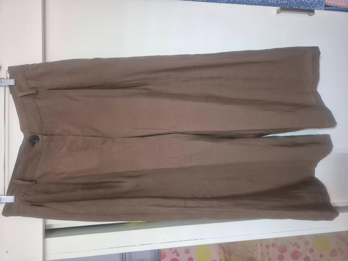 Wide-leg brown trousers with a button and belt loops, hanging on a hanger against a white background.