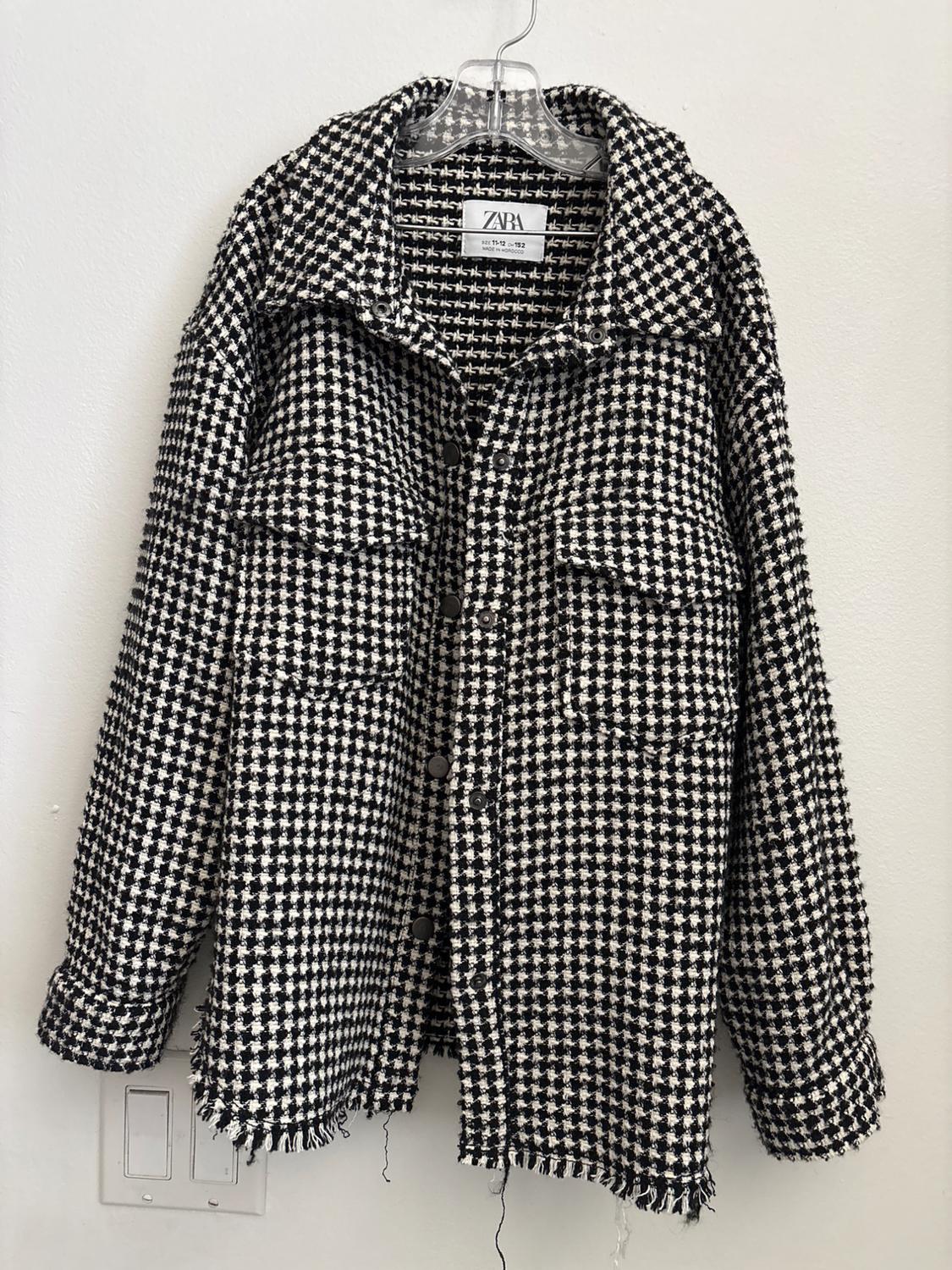 Front view of a black and white checkered jacket with front pockets and buttons.