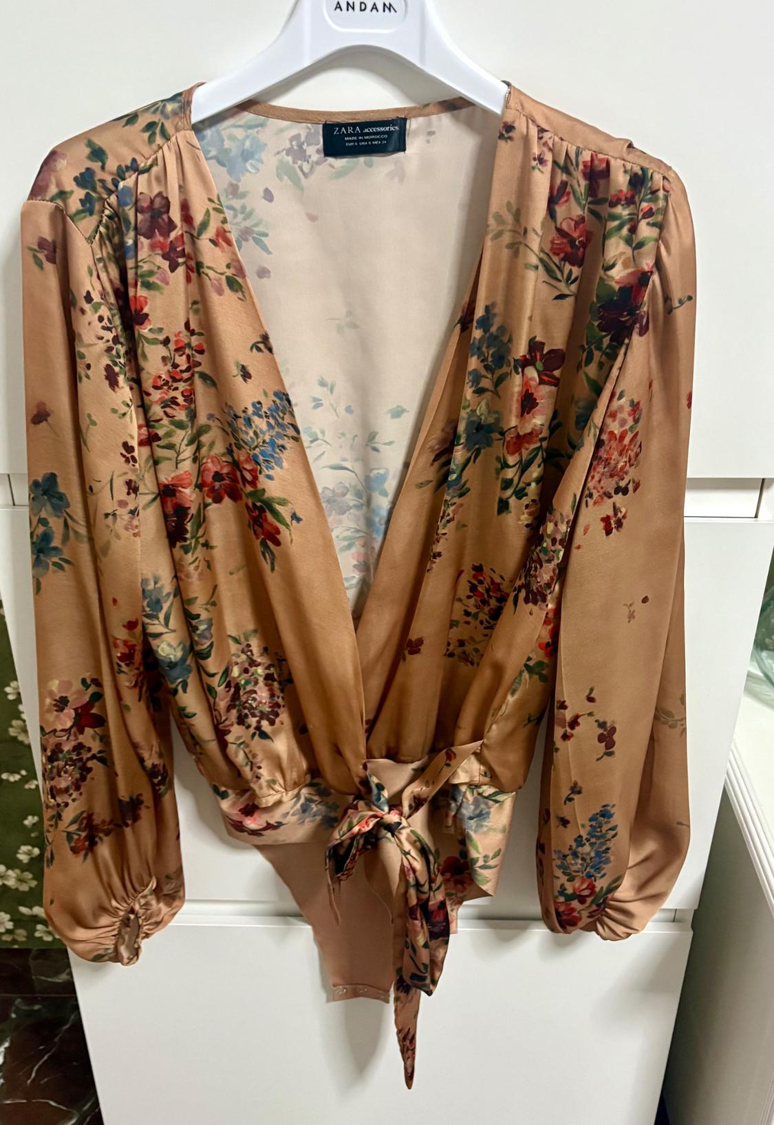 Beige satin blouse with a red and blue floral print, puffed long sleeves, and a tie waist.