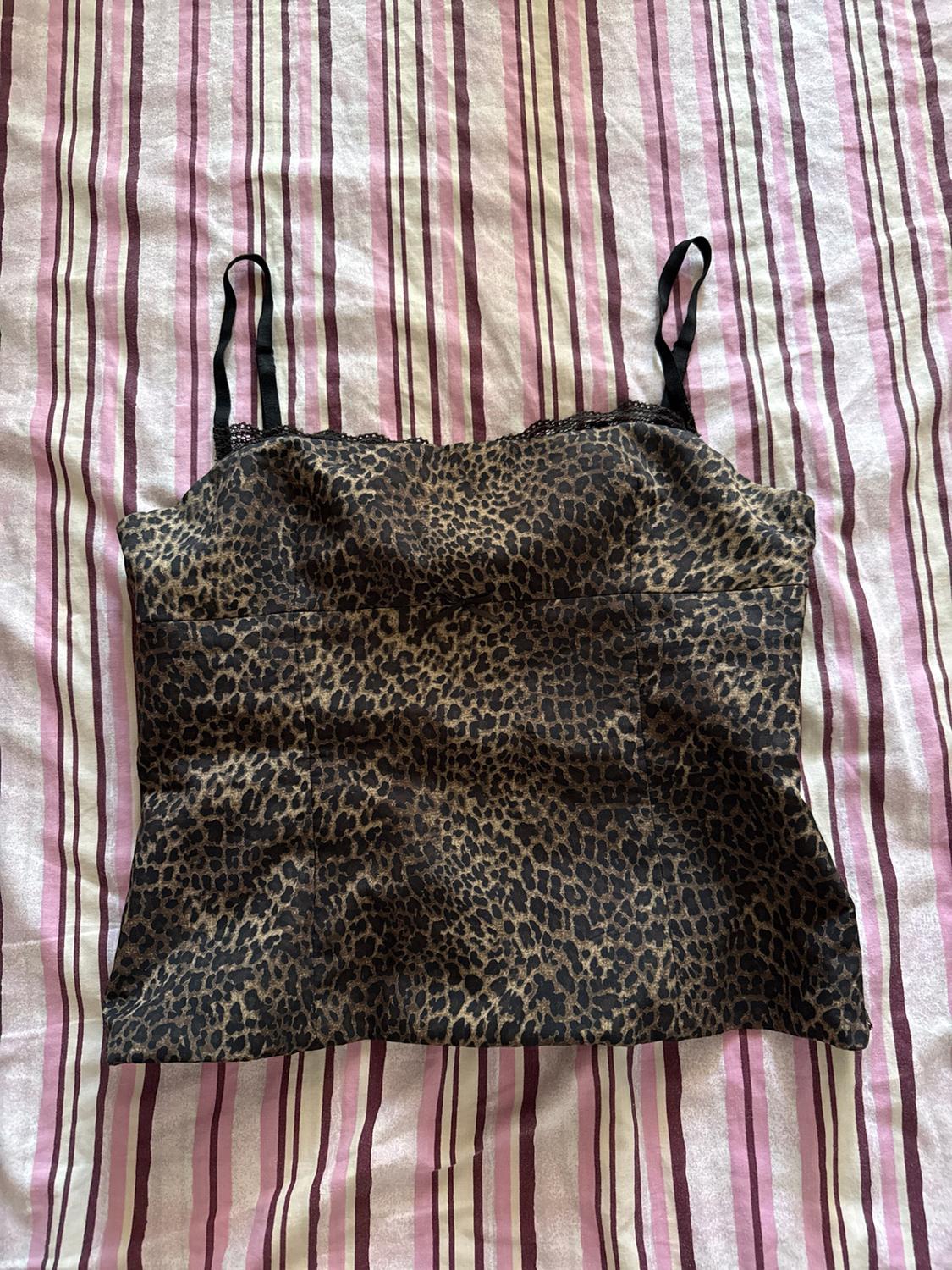 Leopard print camisole with black lace at the neckline, on a pink and white striped fabric background.