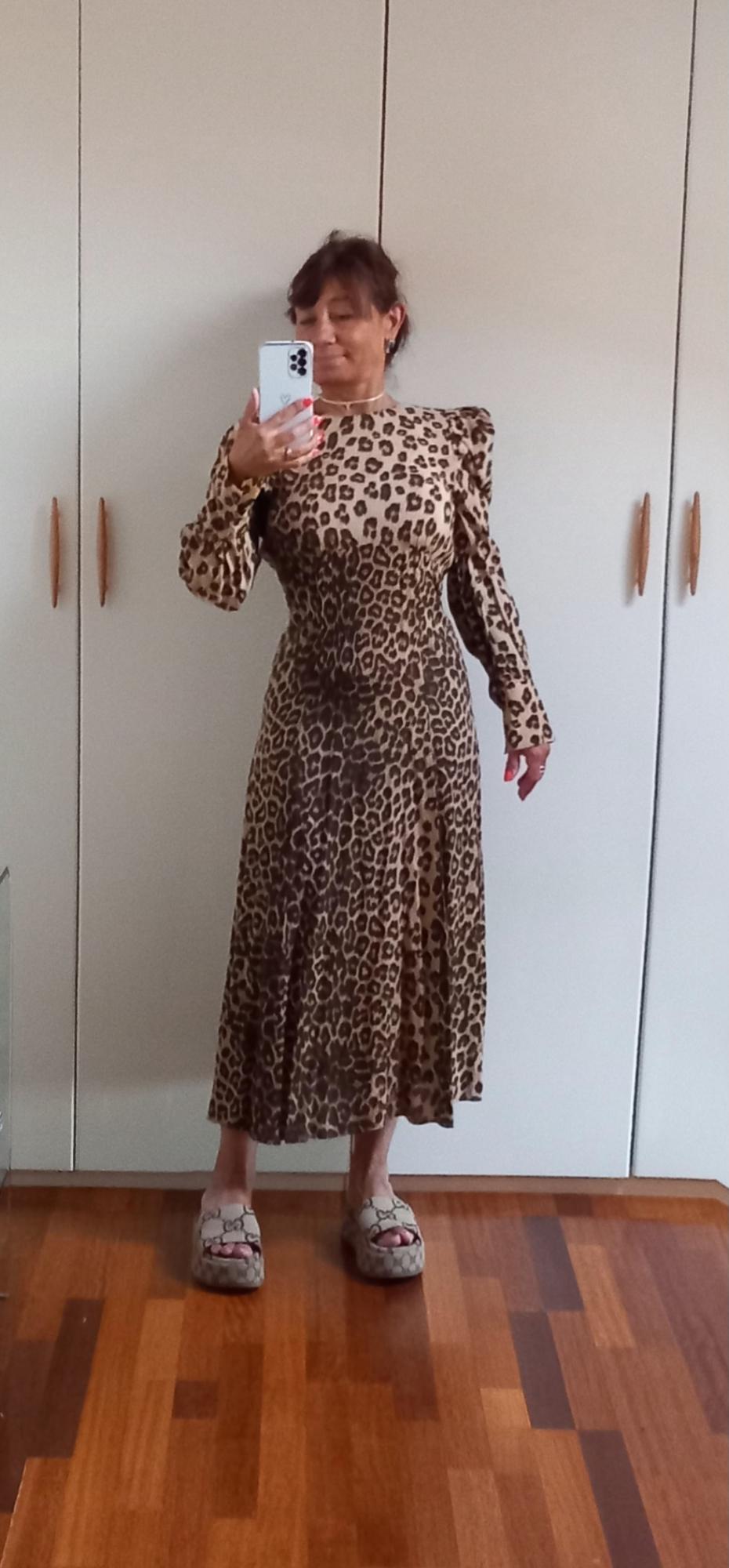 Γυναίκα με φόρεμα με animal print και μακριά μανίκια, βγάζει selfie σε καθρέφτη. Φοράει σανδάλια και βρίσκεται σε δωμάτιο με ντουλάπα.
