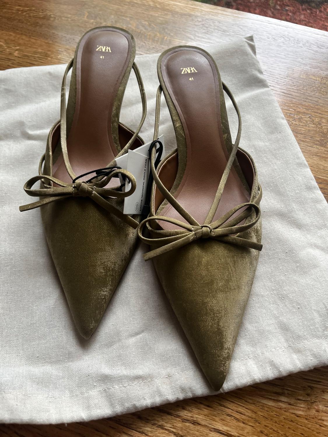 Olive green high heels with bow, ZARA brand, size 41, on white fabric and wooden background.