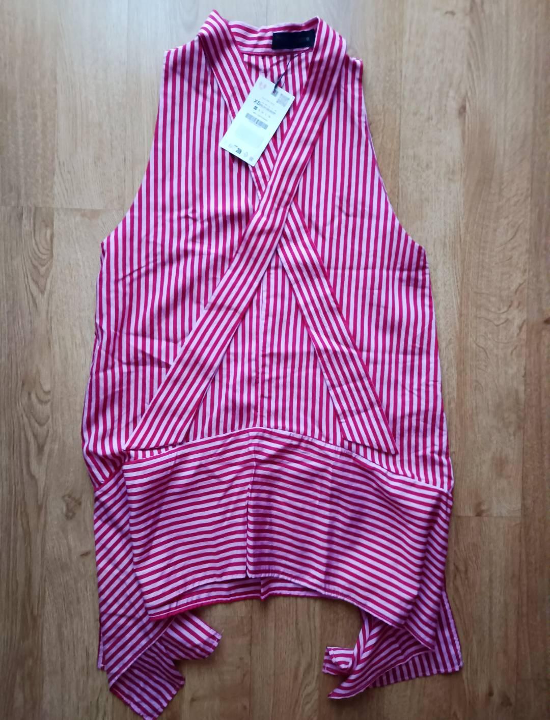 Pink and white striped top, vertical on the top part and horizontal on the asymmetric hem. Wrap design, on a wooden floor. Size XS label.