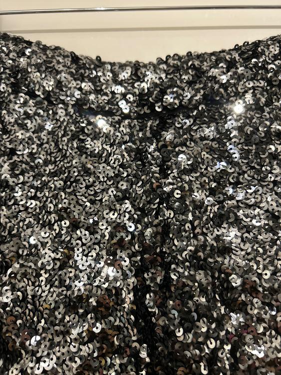 Fabric covered in shimmering silver sequins, creating a dazzling and textured effect against a light background.
