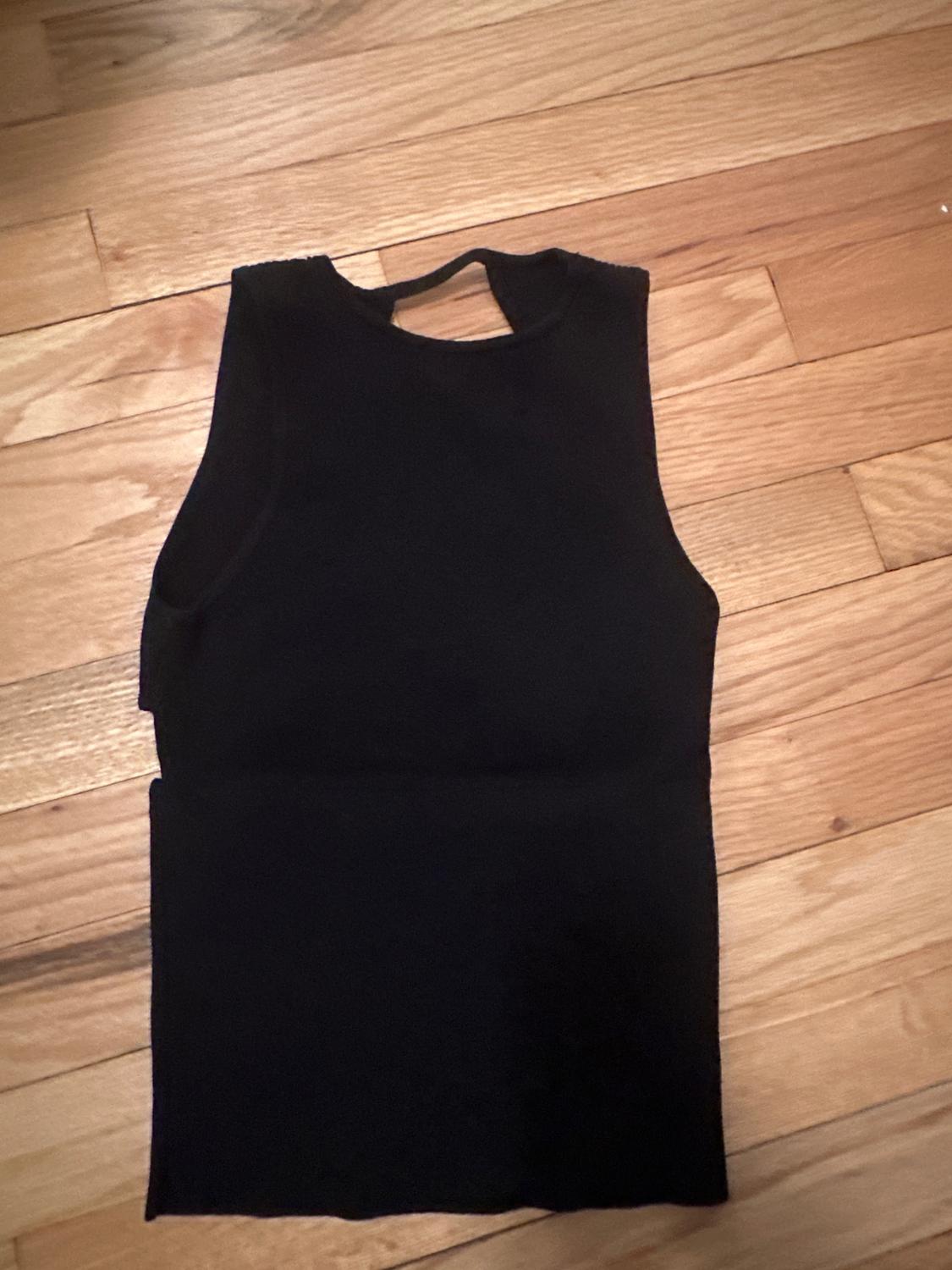 Black sleeveless top on light wood flooring.