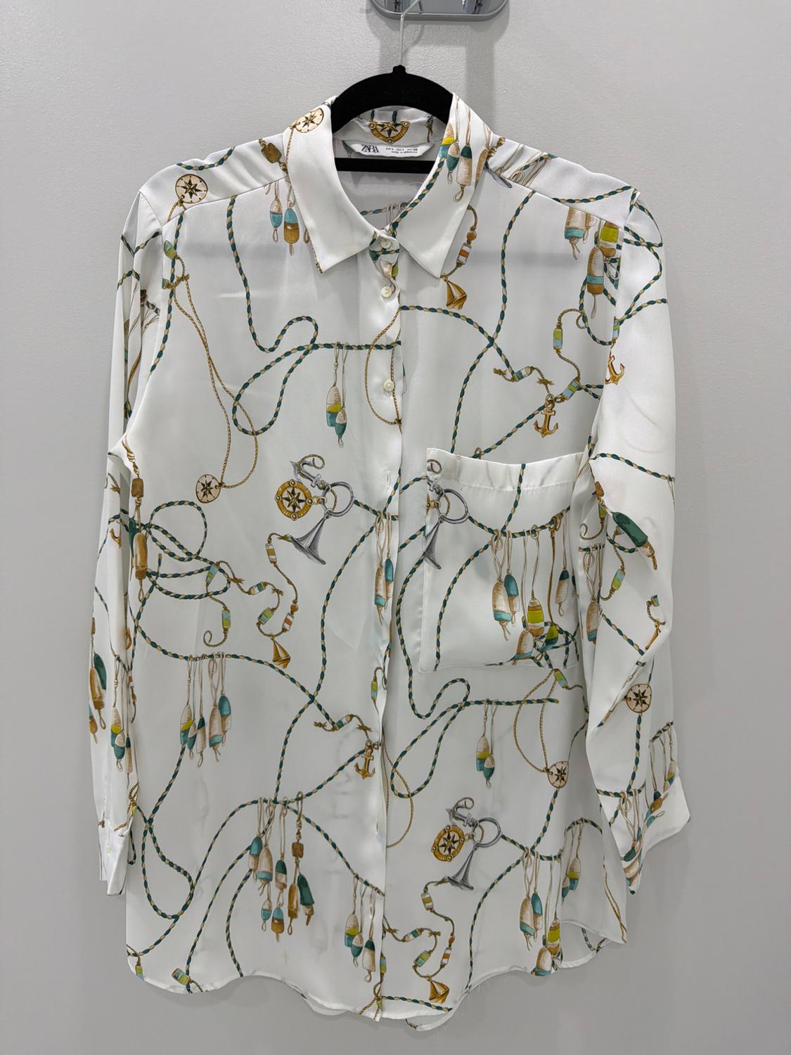 White long-sleeve shirt with a nautical print featuring ropes and anchors, hanging on a black hanger. The text ZARA appears on the tag.