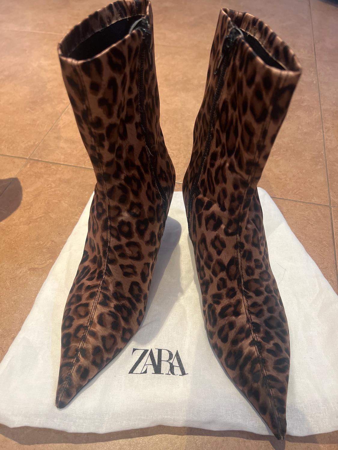 Animal print boots on a white bag with the "ZARA" logo on a brown floor.