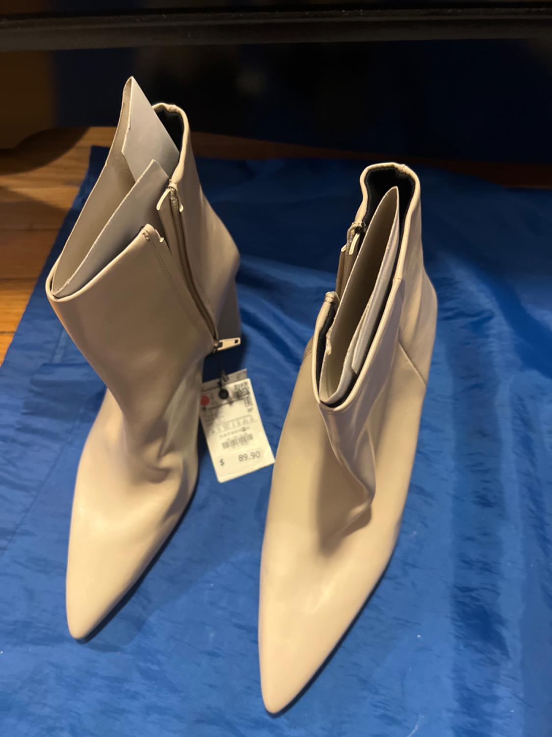 Close-up of beige ankle boots with a side zip and pointed toe.