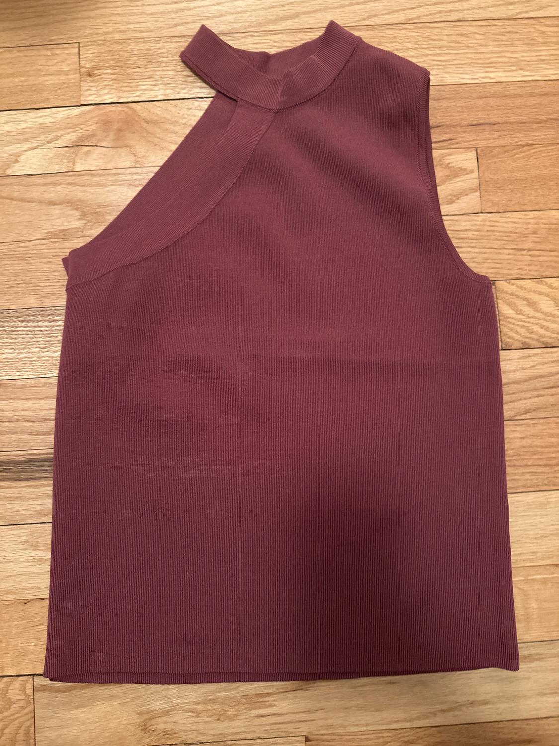 Burgundy sleeveless top with an asymmetrical high collar, on a light wood floor.