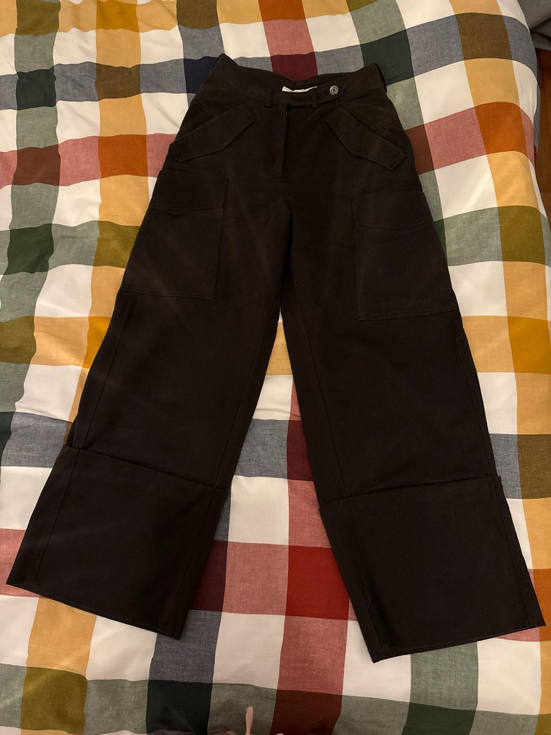 Dark trousers with wide legs, cargo pockets and a wide turn-up hem, on a multi-colour check fabric.