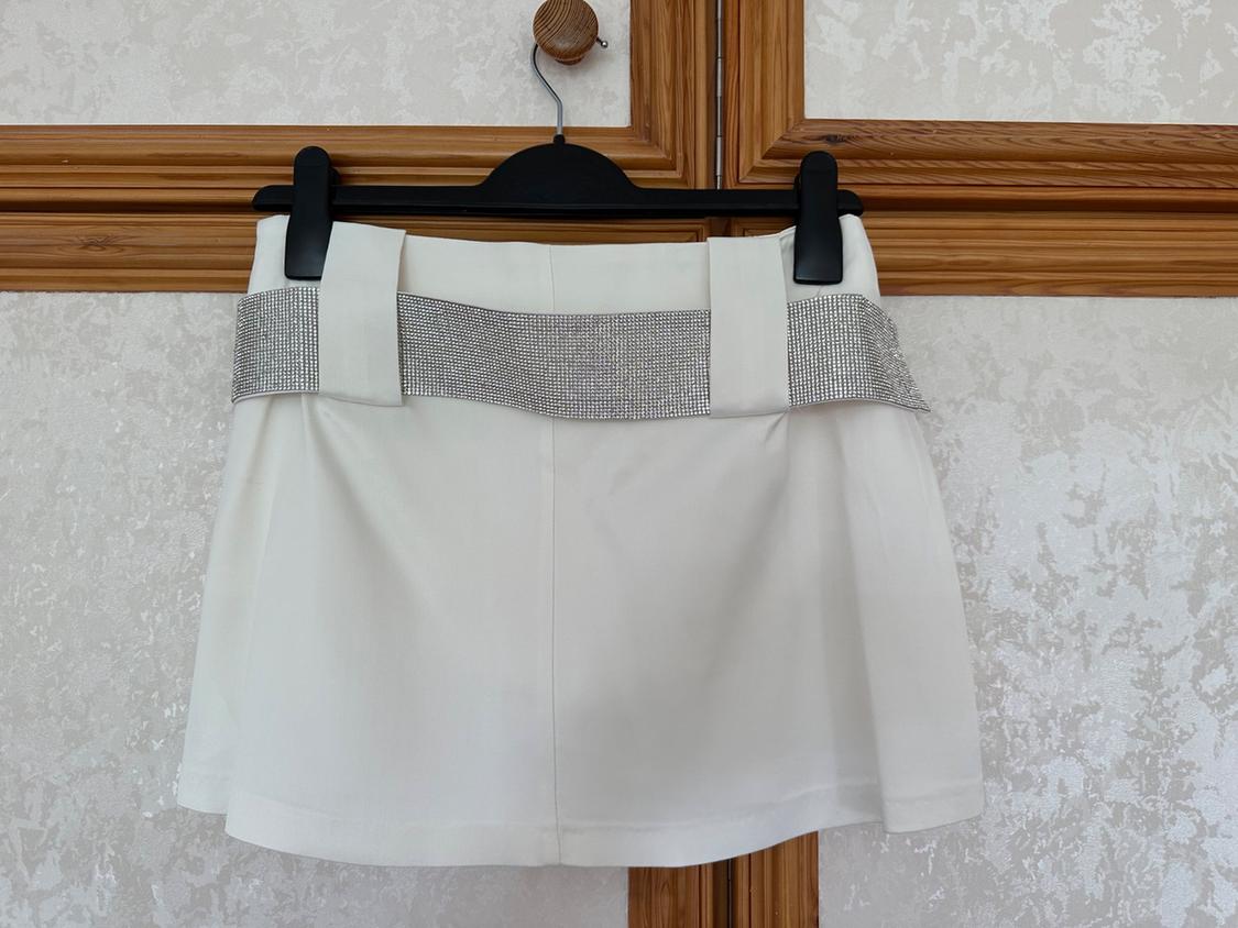 Front view of white skirt with decorative silver belt.
