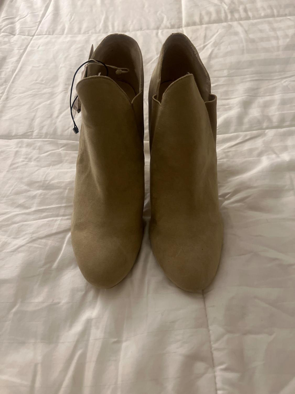 Front view of beige ankle boots with a lace-up fastening at the back.