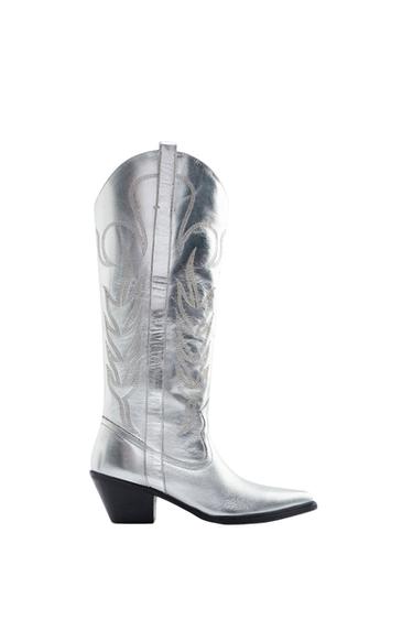 Side view of a silver boot with decorative embroidery and a black heel.