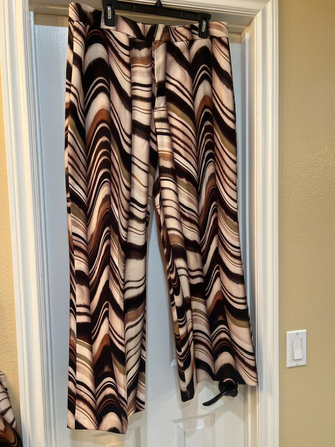 Trousers hanging on a door, with a wave pattern in shades of brown, black, and beige. Interior setting with warm light.