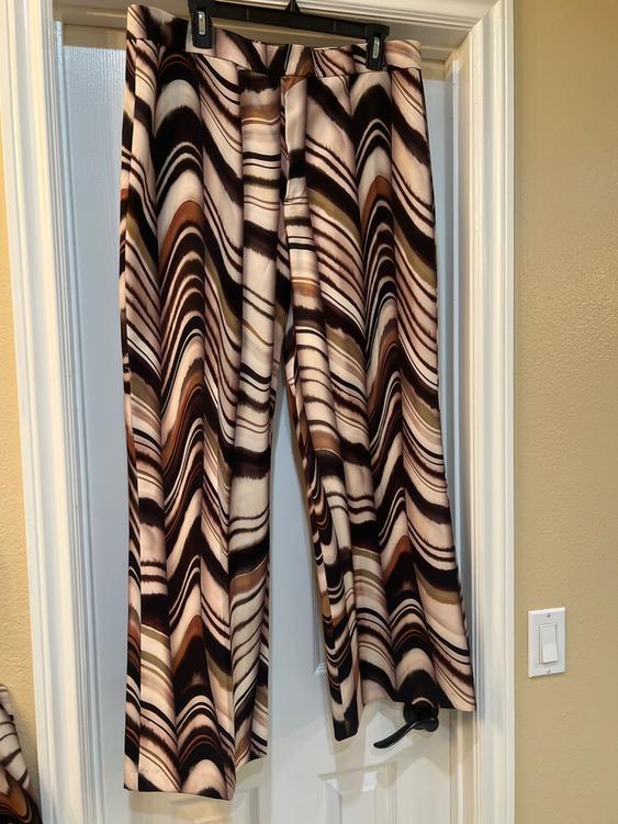 Pants hanging on a door, with a wave pattern in brown, black, and beige tones. Indoor setting with warm light.