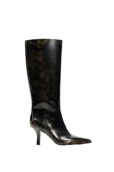 Black leather knee-high boot with a glossy finish and a stiletto heel. White background.