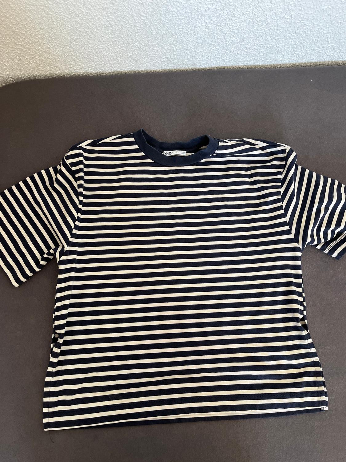 Black and white horizontal striped t-shirt on a grey surface. Visible label on the collar.