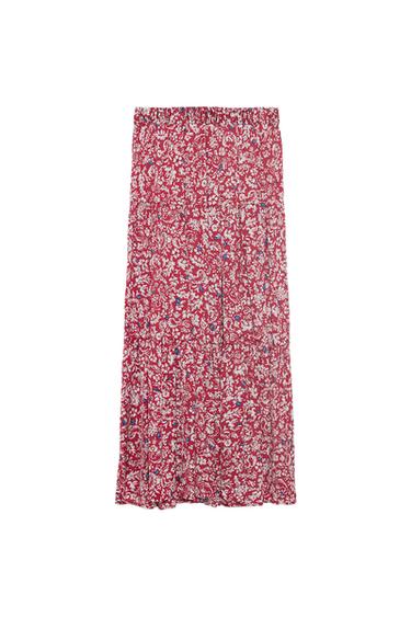 Long red skirt with a white floral print and blue details. Elasticated waist and tiered design on a white background.