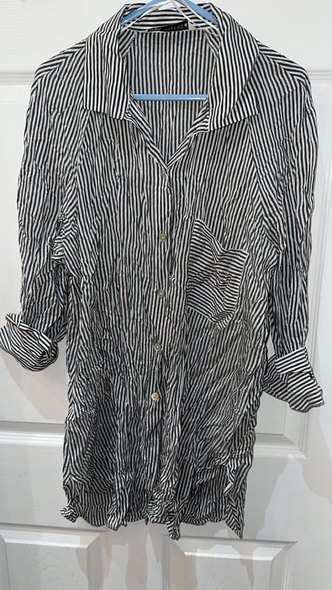 Front view of a black and white striped shirt with a chest pocket and long sleeves.