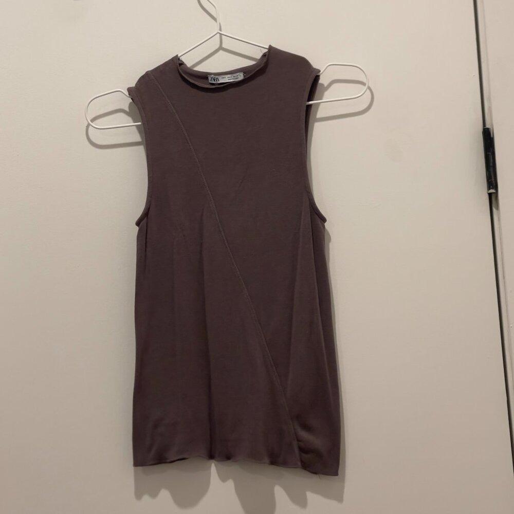 Brown sleeveless shirt with diagonal front stitching, hanging on a white hanger. Visible Zara tag on the neck.