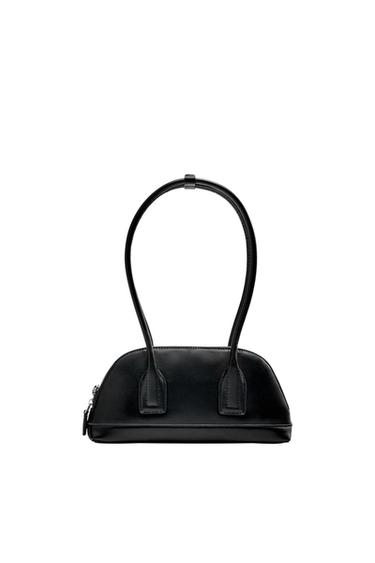 Minimalist black handbag with a semicircular shape, flat base, long handles, and side zip fastening, on a white background.