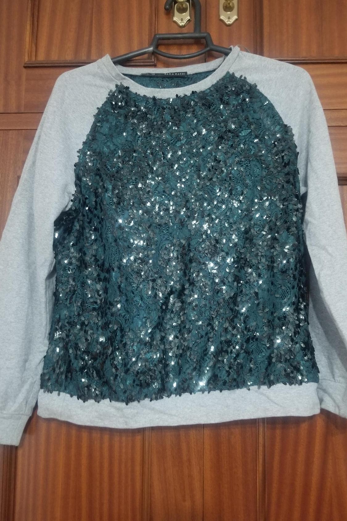 Front view of grey jumper with black sequins on the chest.