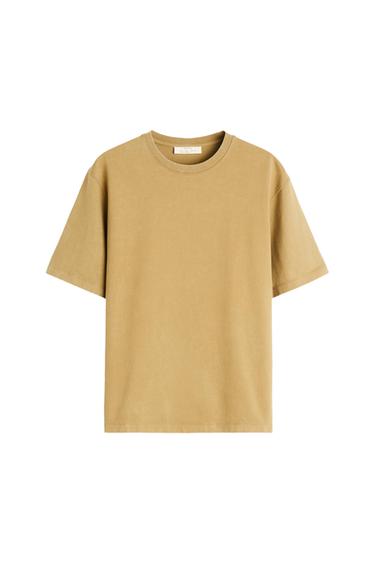 Beige short-sleeved, round-neck T-shirt, hanging on a white background. Label visible on the inside of the collar.