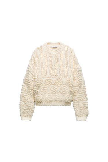Front view of a cream-colored, chunky knit sweater with texture and a crew neck.