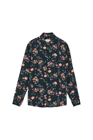 Long-sleeved shirt with a floral print in orange and green tones on a dark background. Classic collar and button fastening.