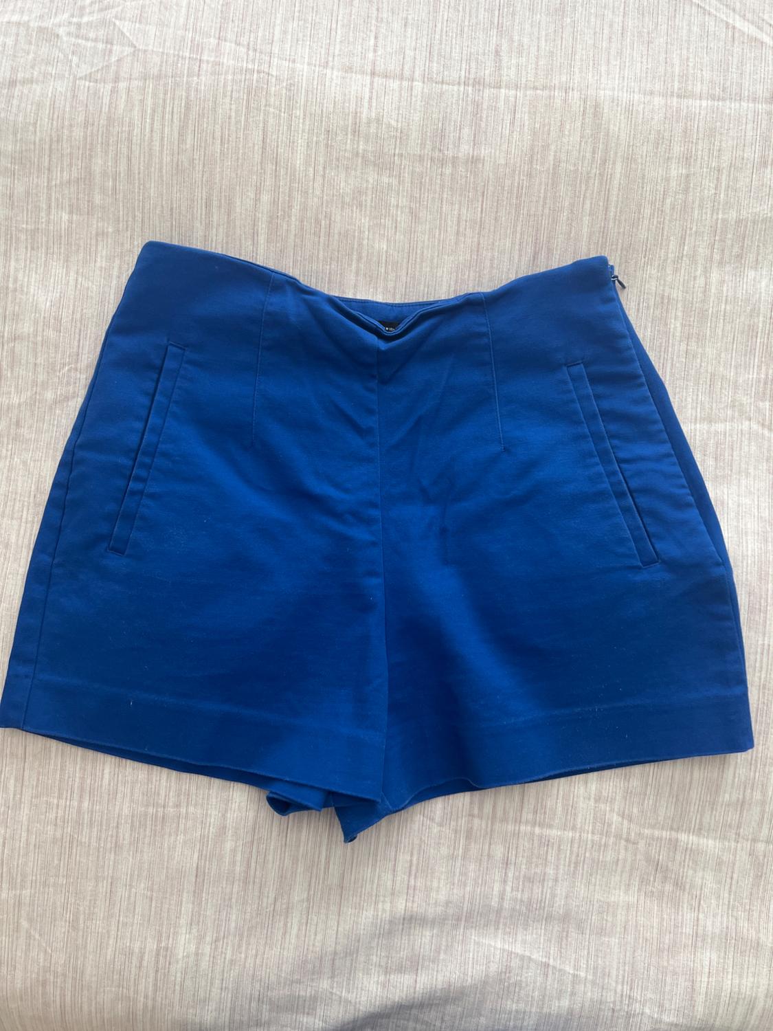 Blue shorts on a light surface. Simple design with side pockets and front fastening.