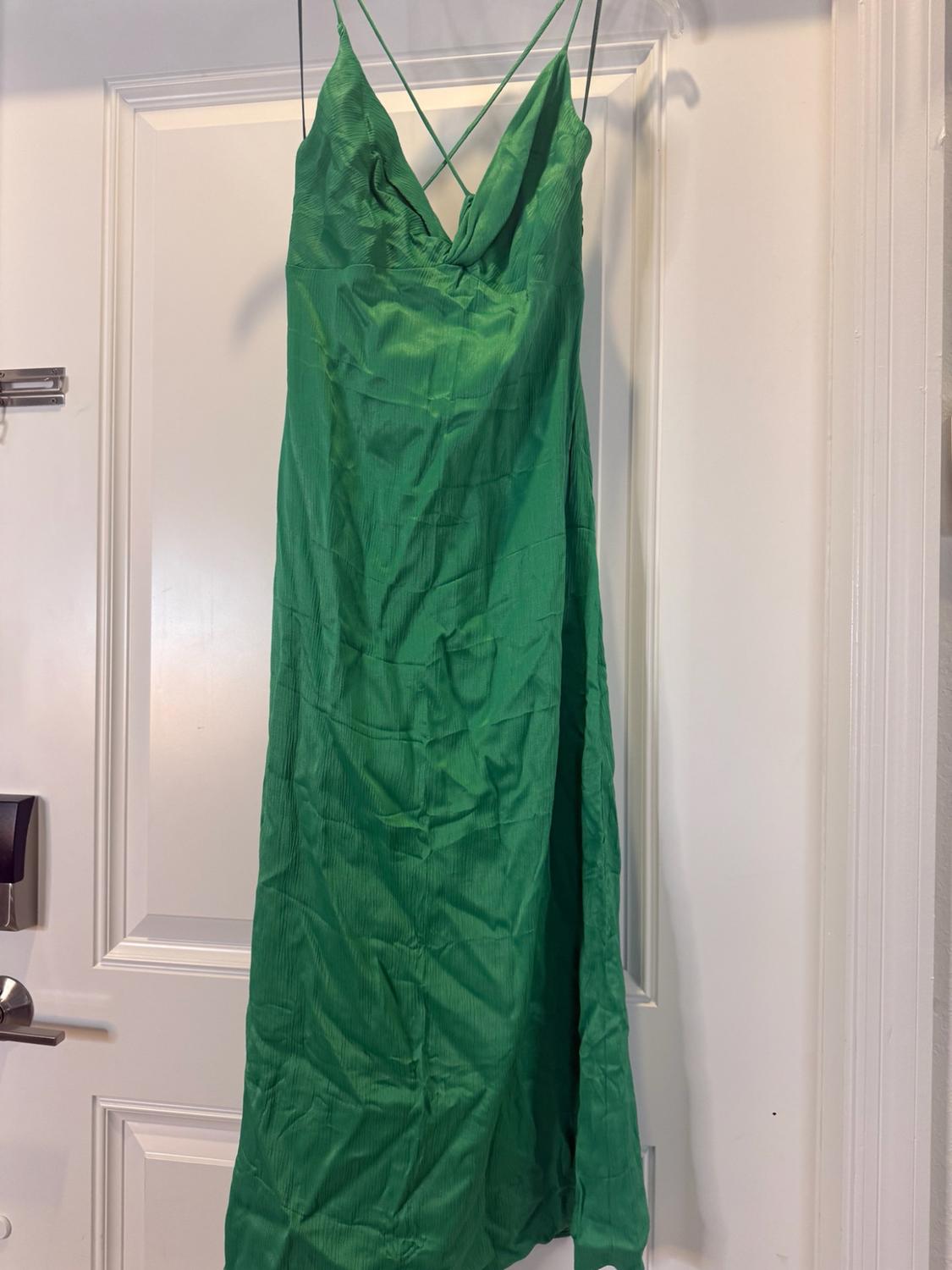 Long green dress with fine crossed straps, hanging on a white door.