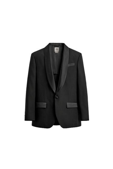 Front view of black blazer with shawl lapel, one-button closure, jetted chest pocket and flap pockets at hip.