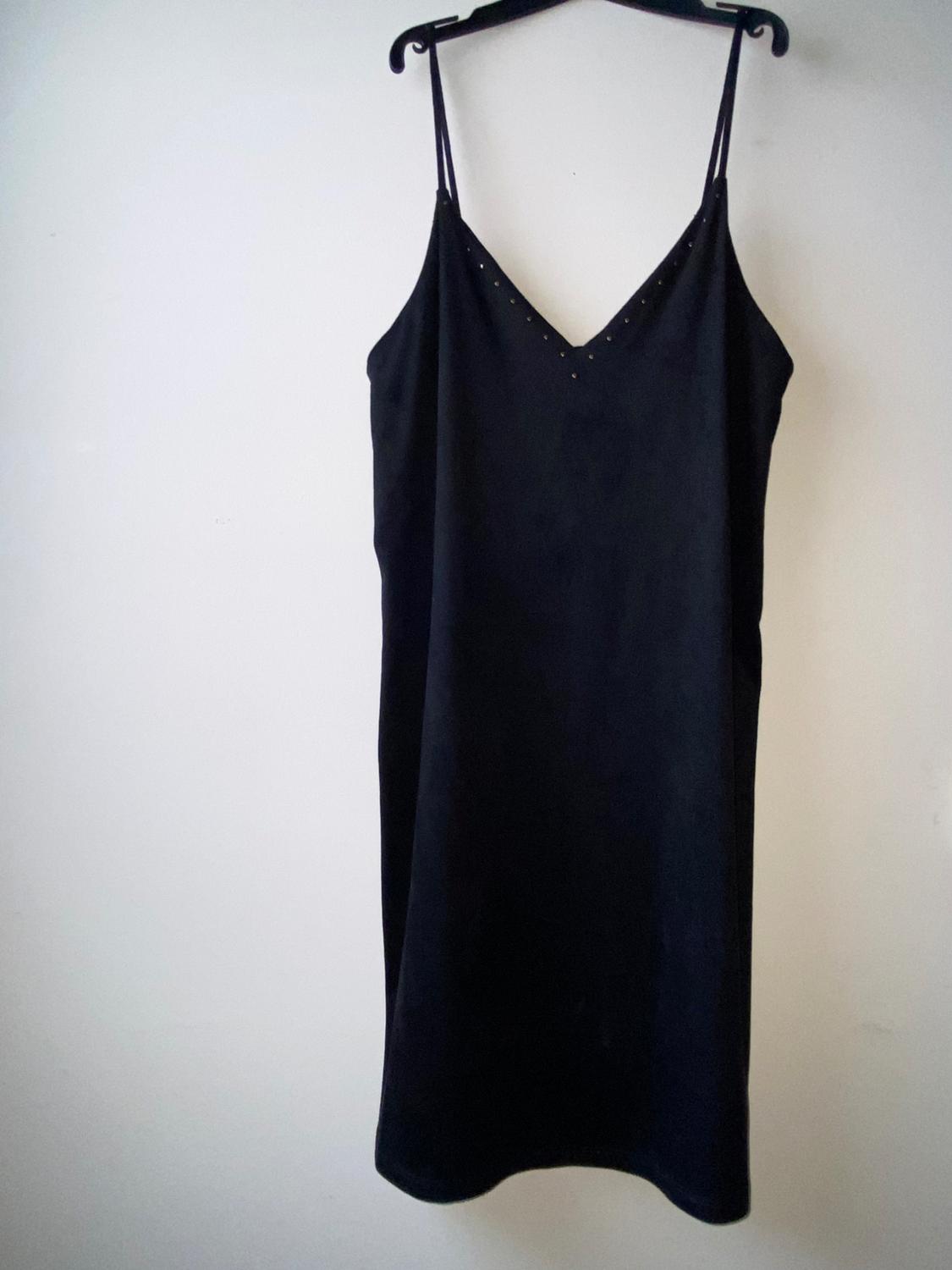 Black slip dress with a V-neckline embellished with small studs, hanging on a hanger against a white background.