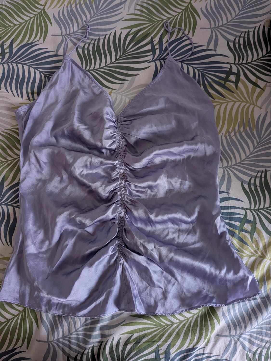 Lilac satin camisole top with thin straps and a ruched centre, featuring a green and blue botanical print background. Relaxed fit.