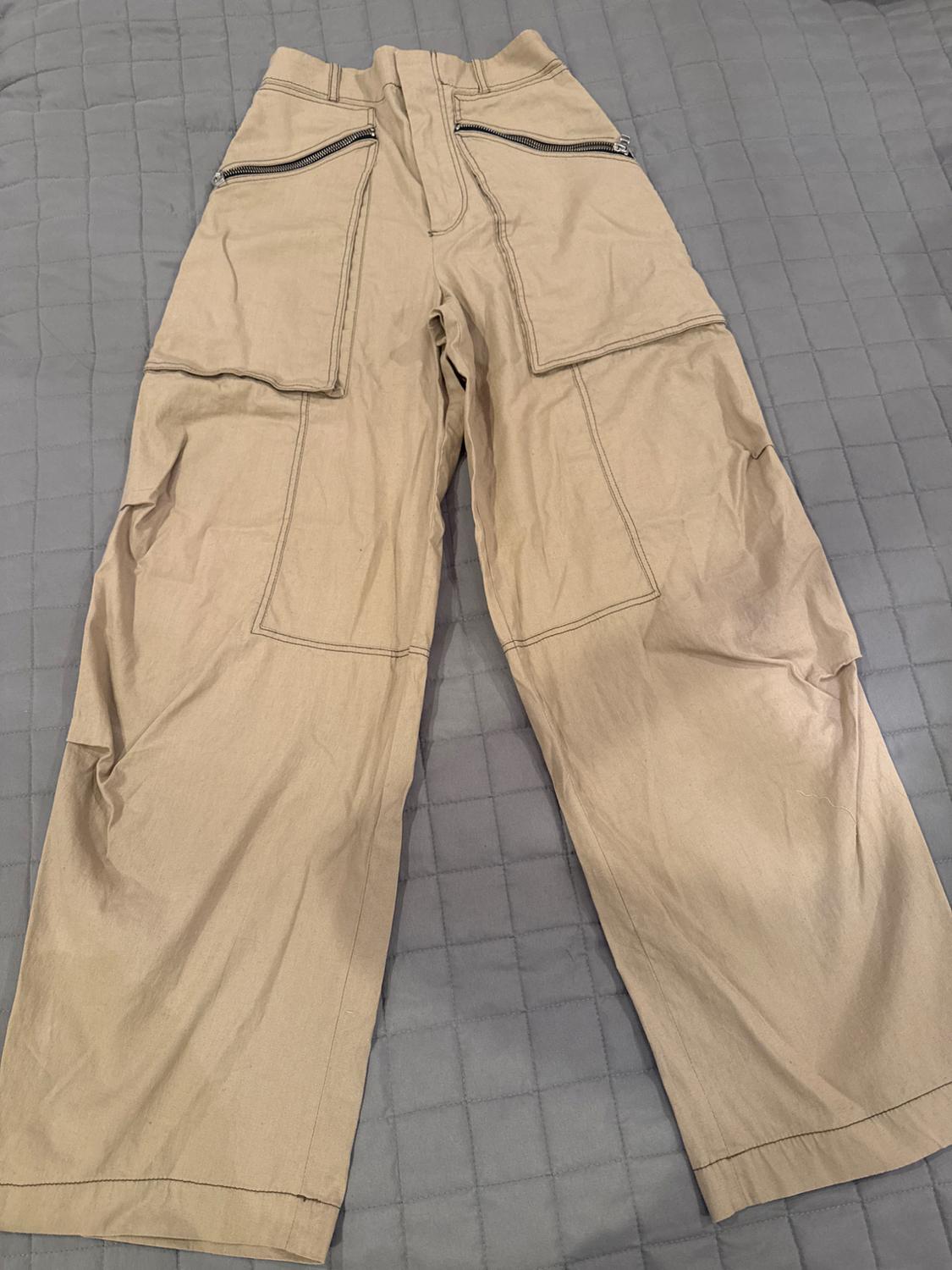 Back view of beige pants with large pockets and zipper closures at the upper back.
