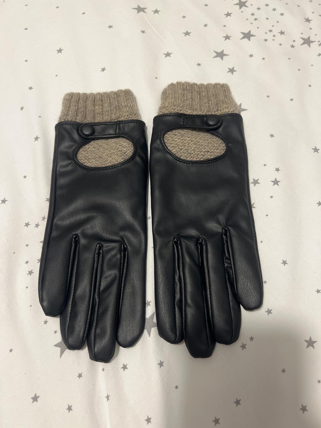 Black gloves with beige knit detail on the cuffs and an oval opening, on a white background with a grey star print.