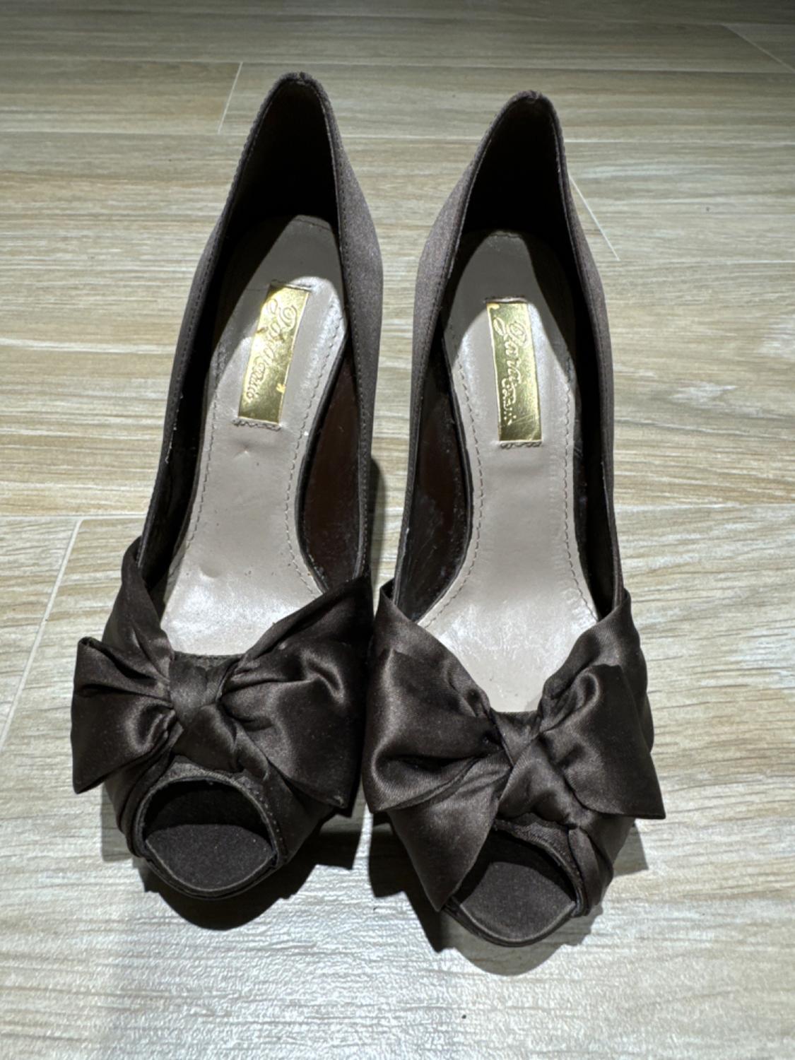 Front view of open-toe brown high-heeled shoes with a bow on the toe.