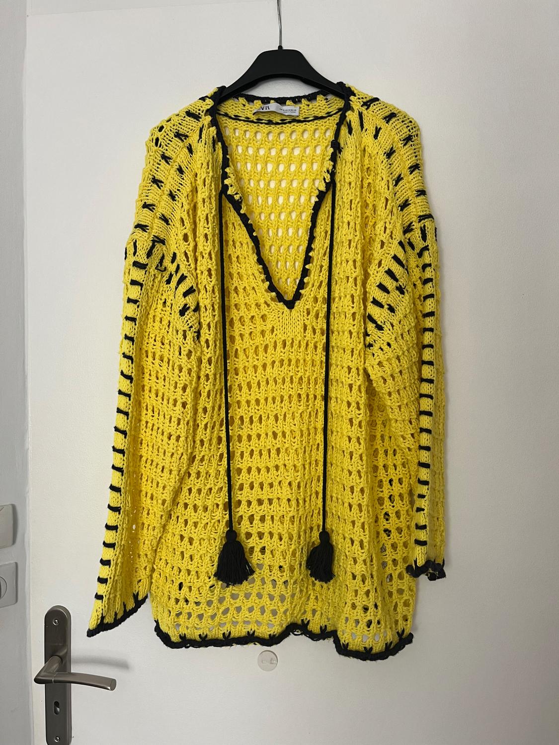 Front view of a yellow knitted jumper with black details and a V-neck.