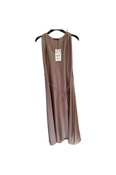 Front view of a sleeveless beige dress with a tie at the waist and a visible label.