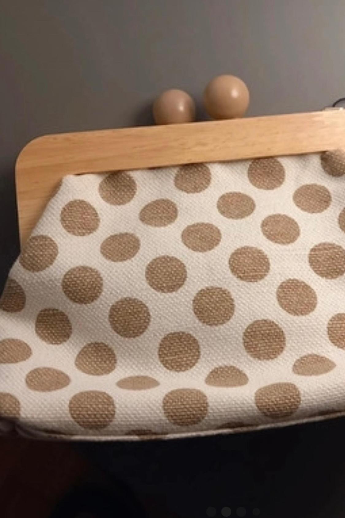 Close-up of a beige polka dot handbag with a wooden clasp.