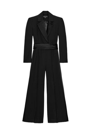 Front view of black jumpsuit with lapel collar, long sleeves, satin cummerbund, front pleats and concealed side pockets.