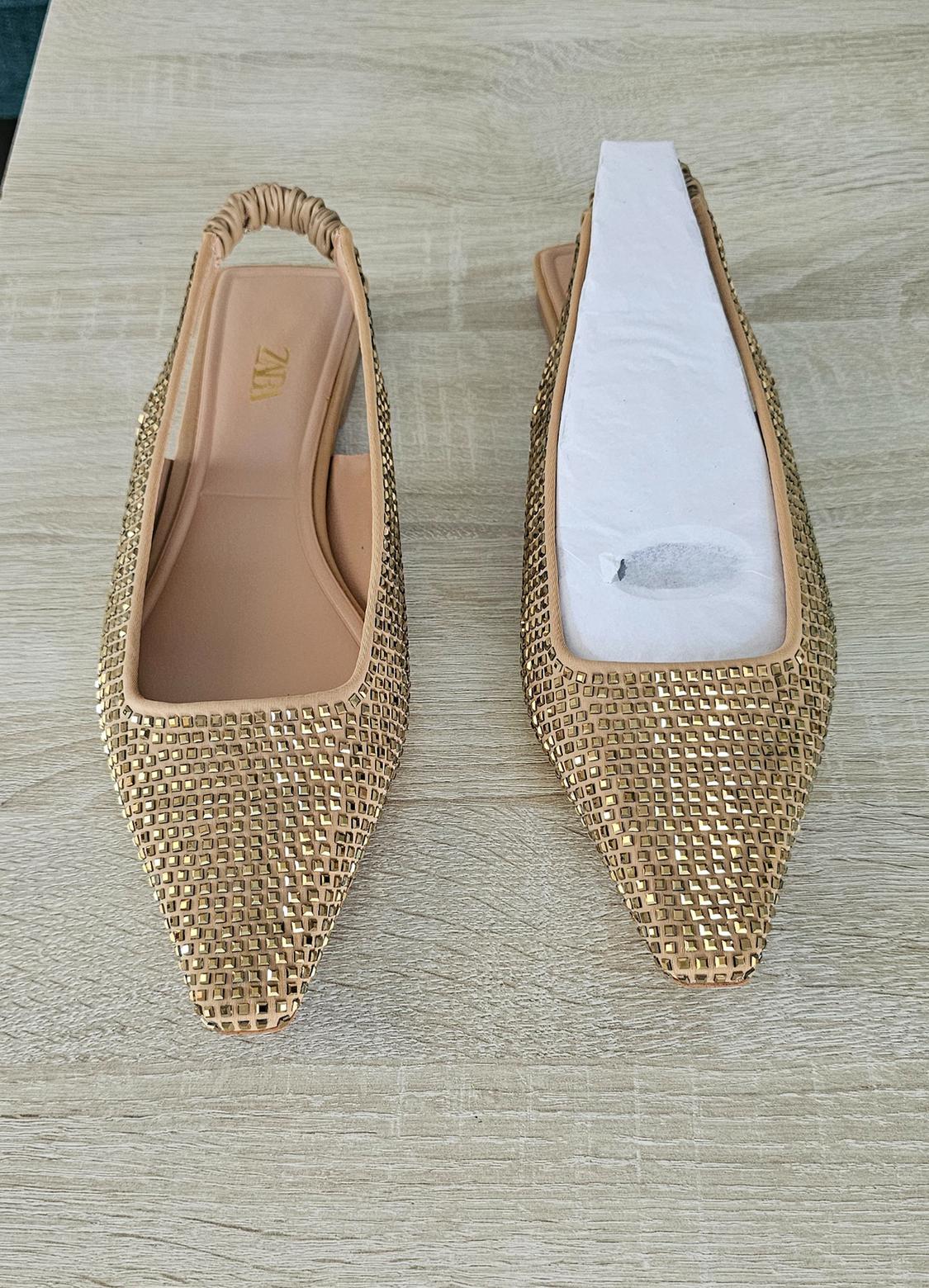 Pointed-toe slingback flats with gold studs on light wood. The left shoe shows the text ZARA.