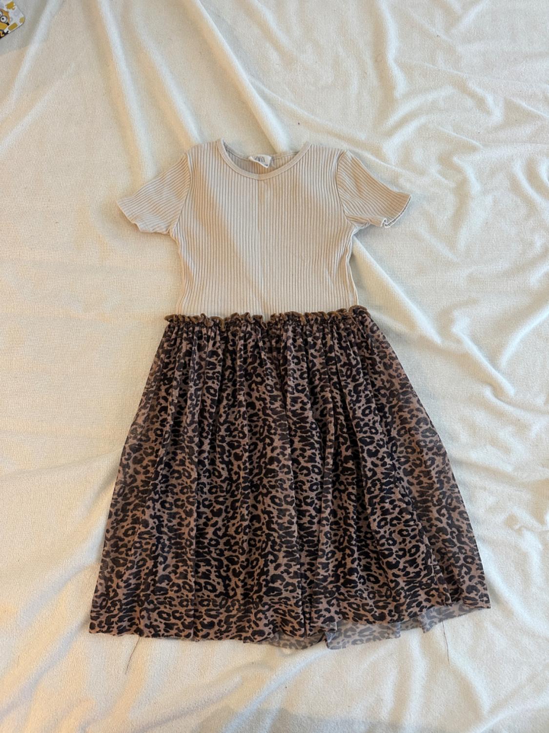 Short-sleeved dress with beige ribbed top and a leopard print skirt on a light background.