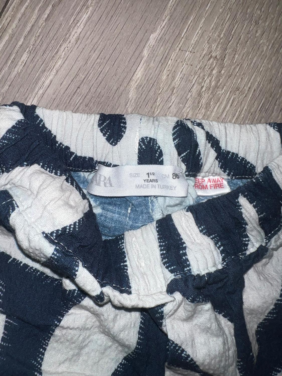 Children's trousers label with blue and white striped design. Visible text: "1 1/2 YEARS, MADE IN TURKEY, KEEP AWAY FROM FIRE".